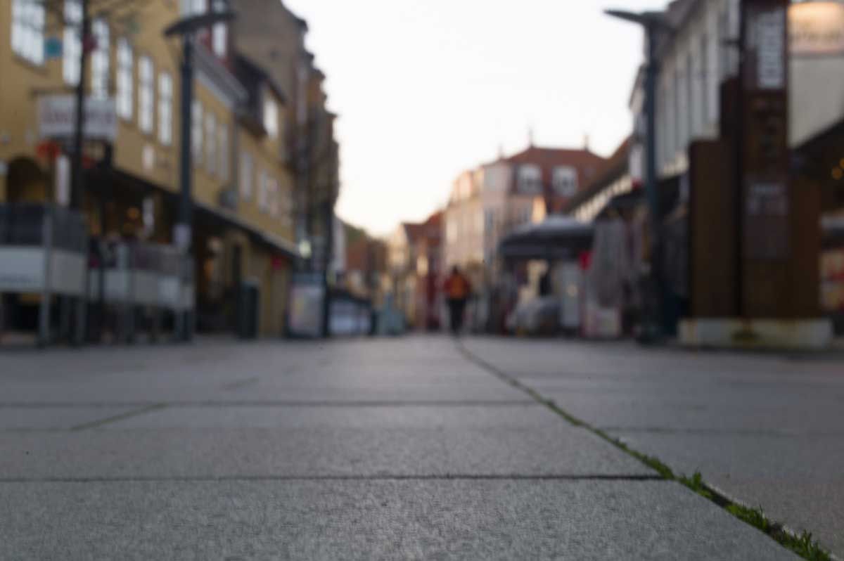 Et sløret billede af en bygade med mennesker, der går ned ad den.