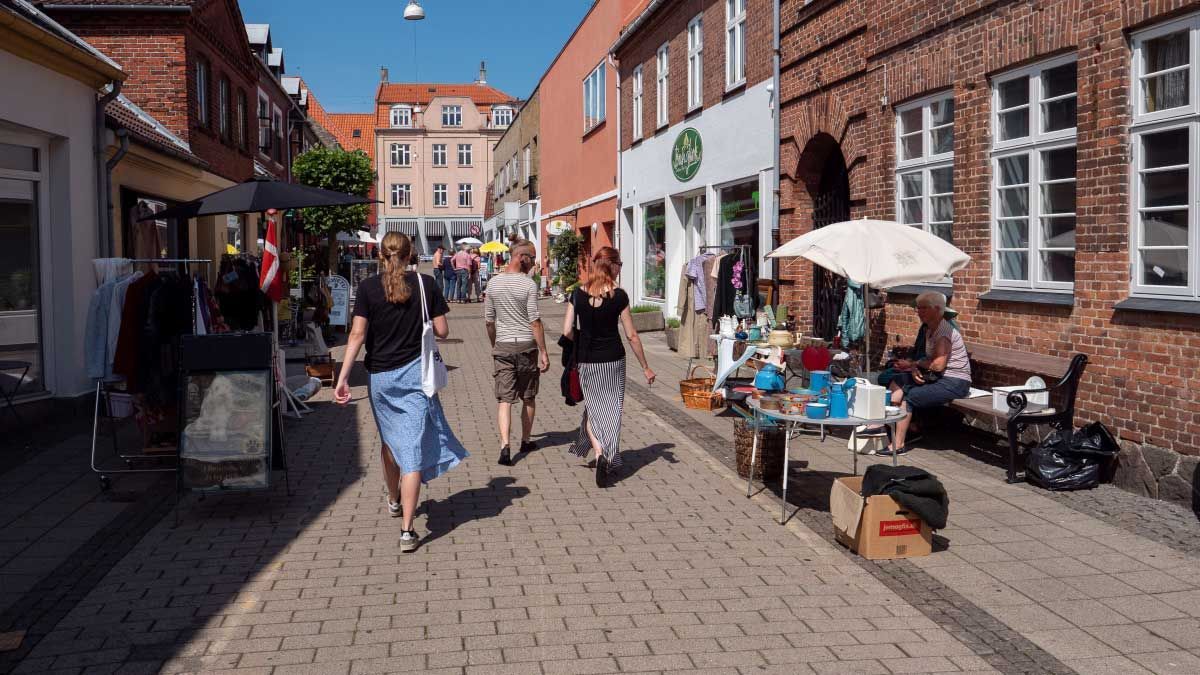 En gruppe mennesker går ned ad en brostensbelagt gade.