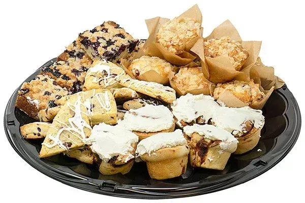 A black platter overflowing with pastries: blueberry squares, scones, muffins, and frosted cinnamon rolls.