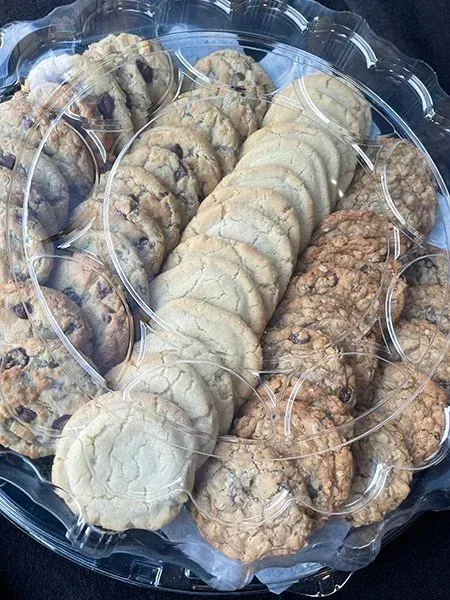 A plastic tray of assorted cookies, including chocolate chip, sugar, and oatmeal.
