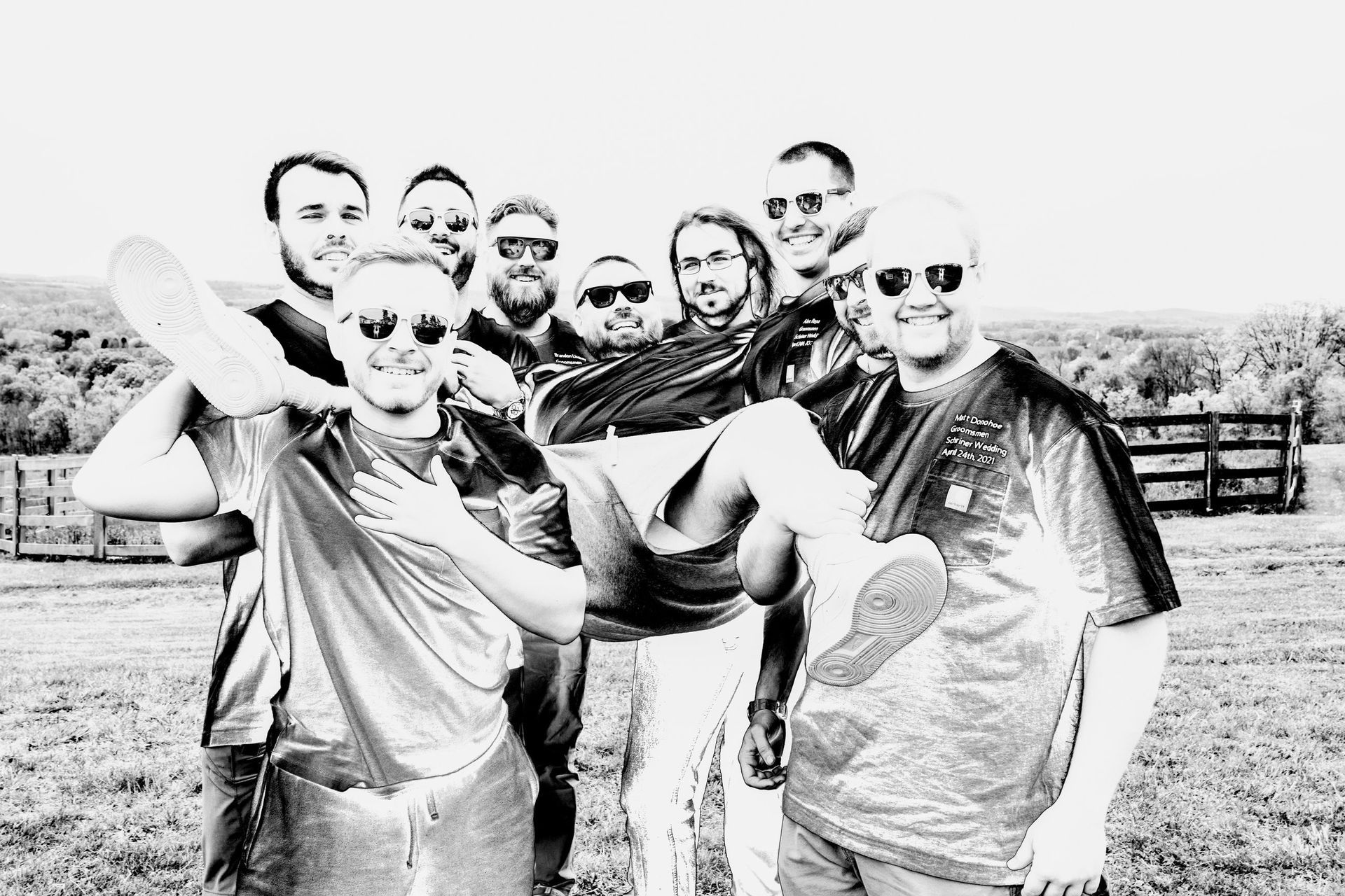 A group of men smiling and posing in a field, some holding items.