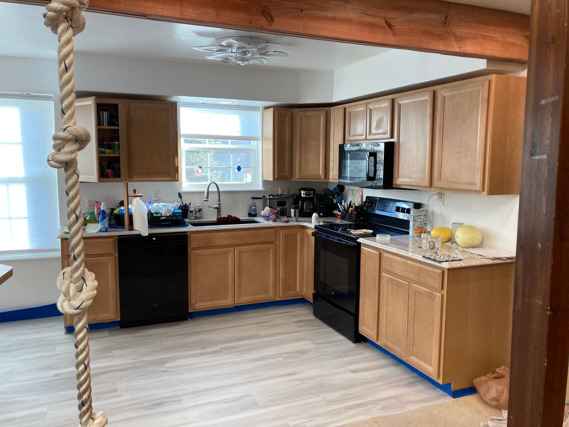 A kitchen with wooden cabinets , black appliances , and a rope swing hanging from the ceiling.