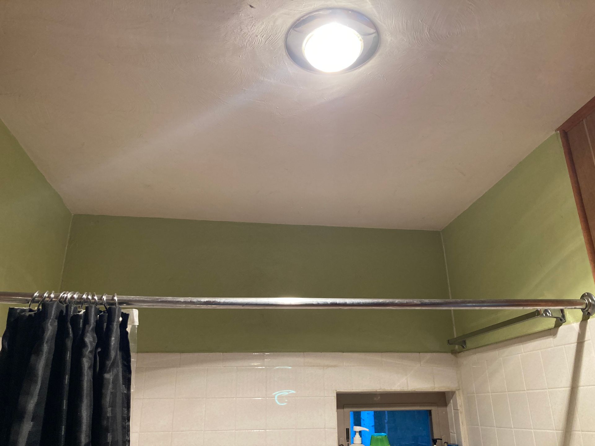A bathroom with a shower curtain and a light on the ceiling.