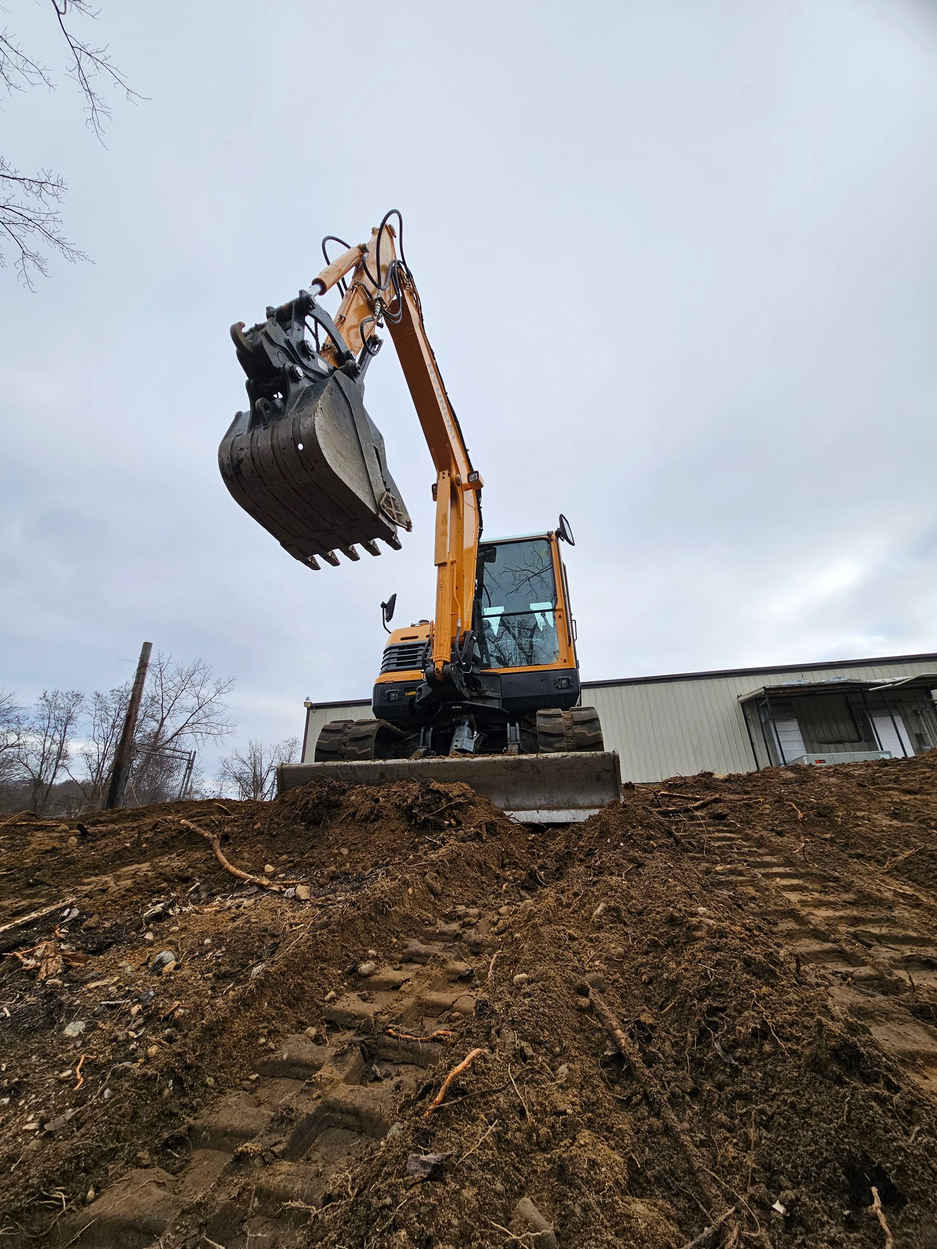 A yellow excavator is moving dirt on a hill.