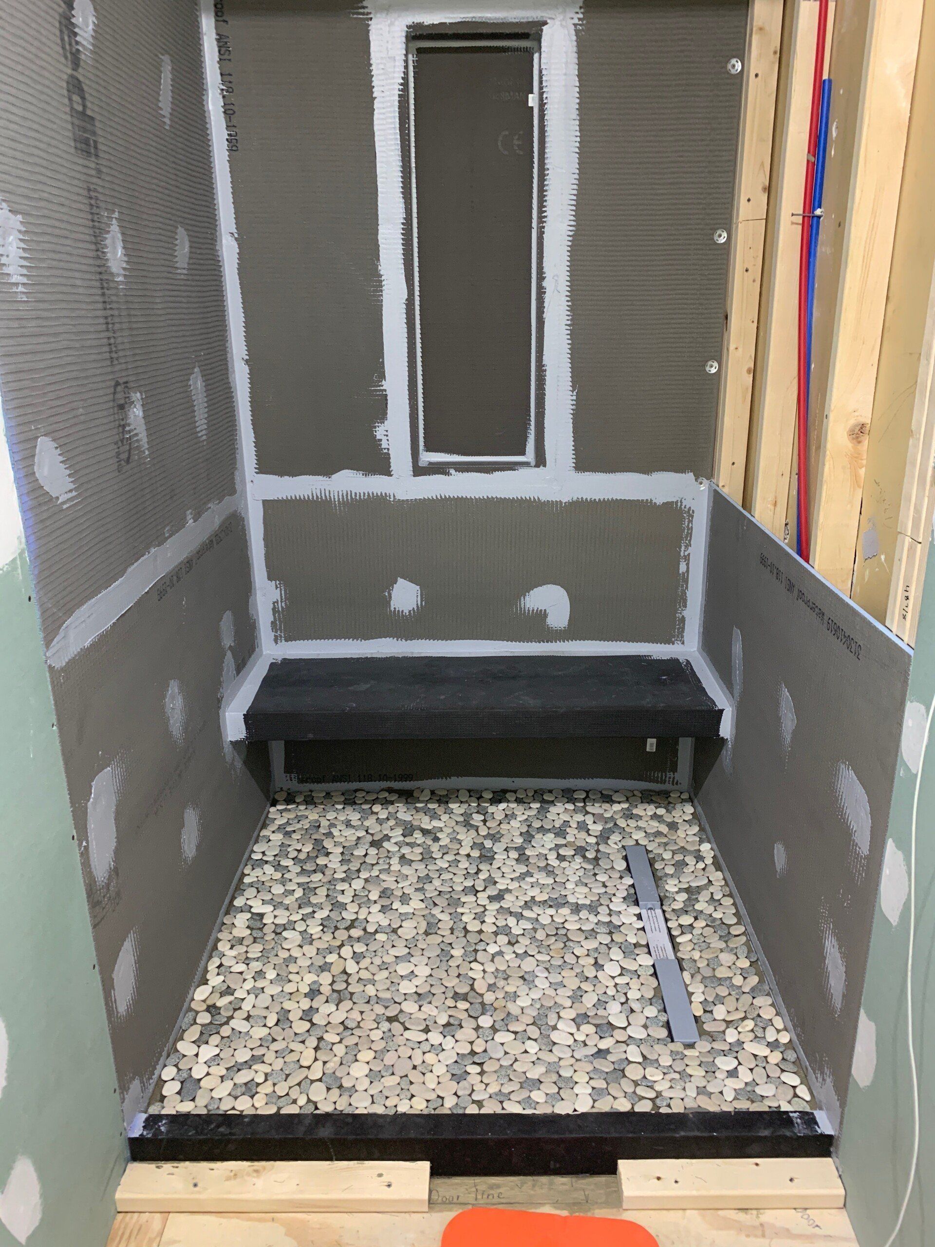 A bathroom under construction with a window and a gravel floor
