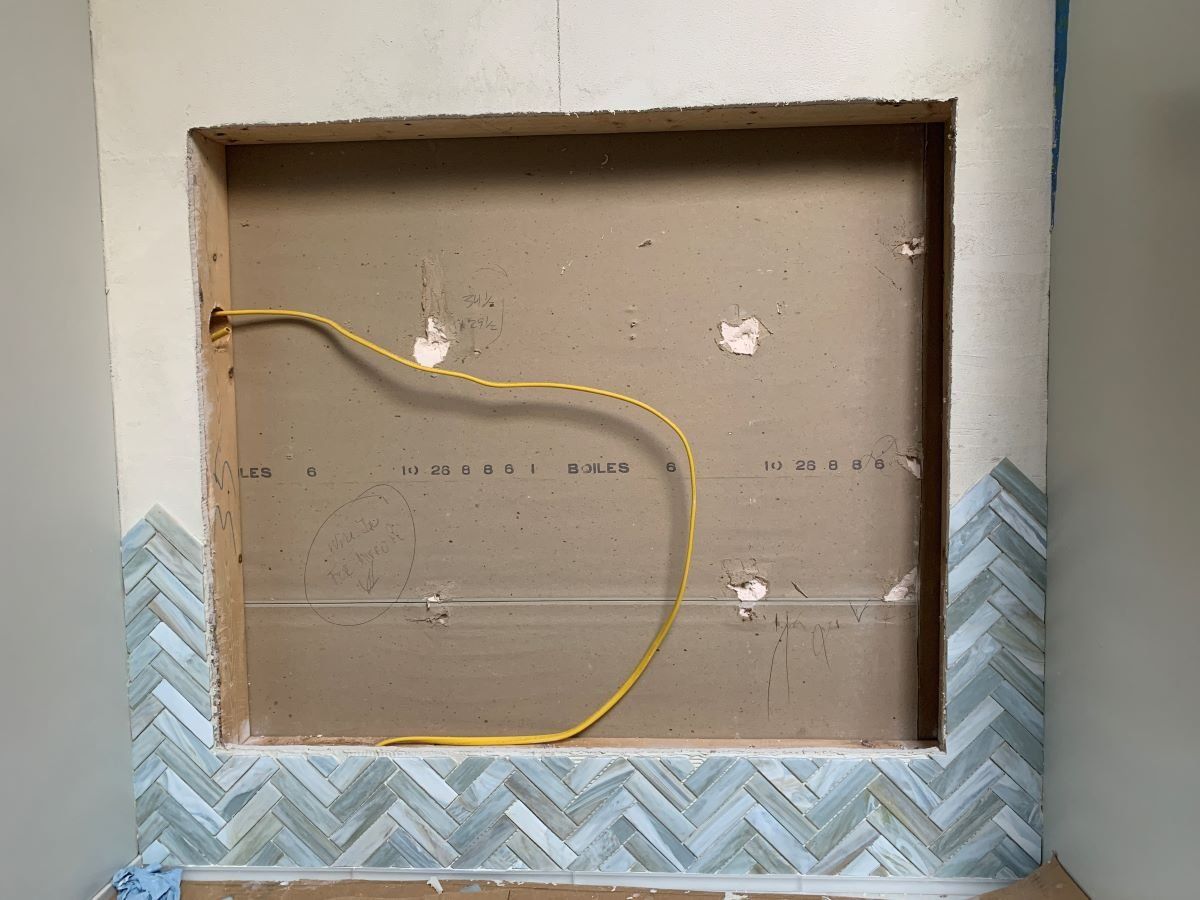A hole in the wall with a yellow wire coming out of it.