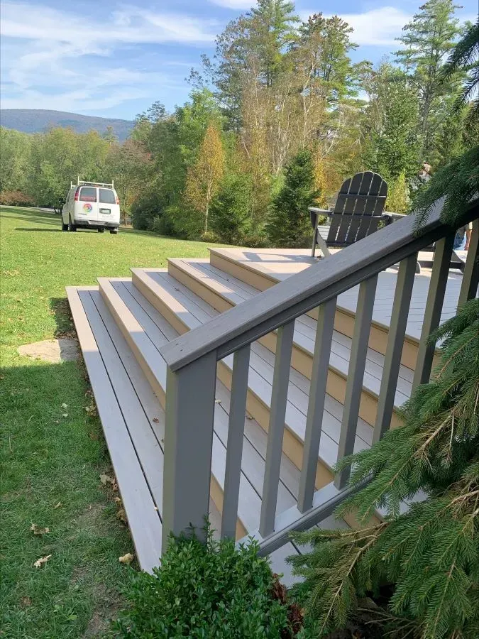 A deck with stairs leading up to it and a van parked in the background.