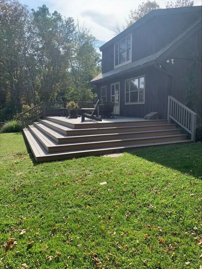 A large house with a large deck and stairs in the backyard.