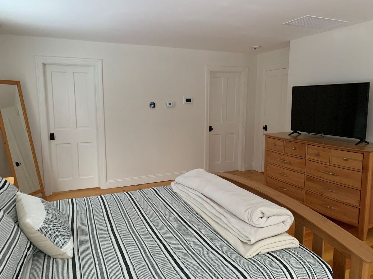 A bedroom with a bed , dresser , television and mirror.