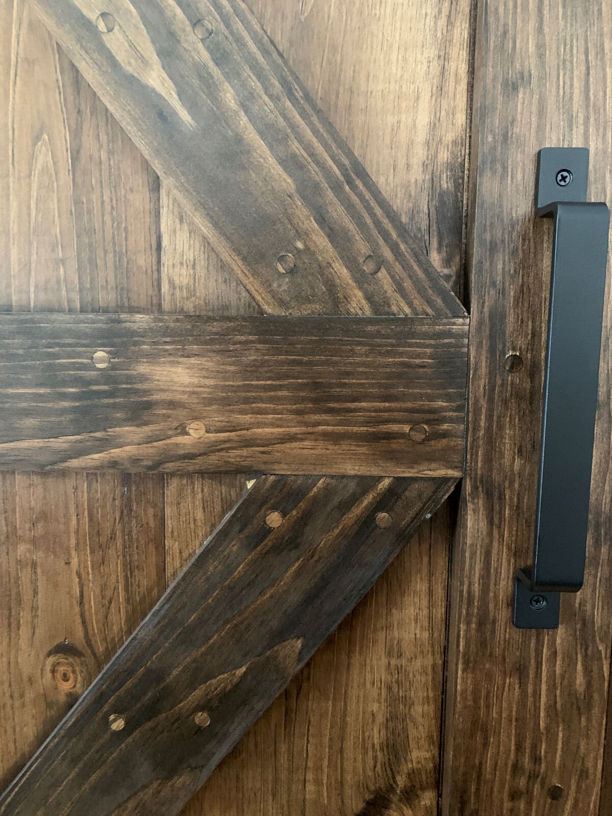 A close up of a wooden door with a black handle.