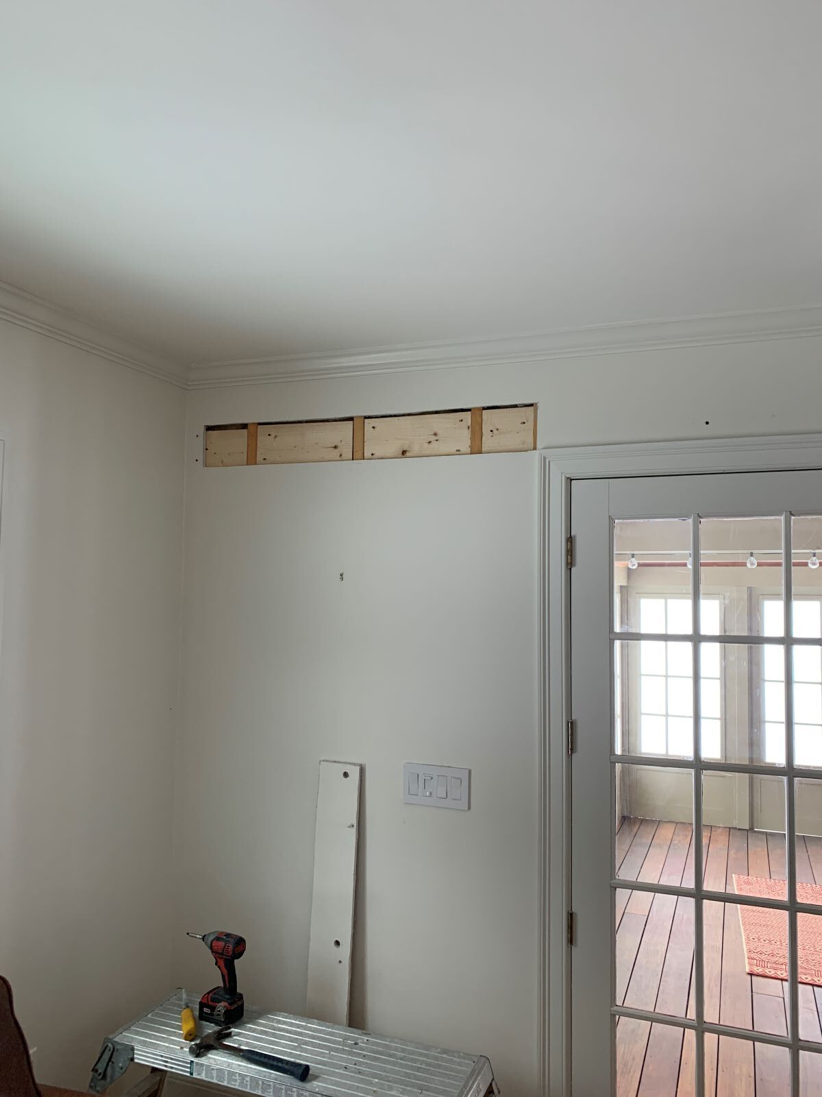 A room with a french door and a table with a drill on it.