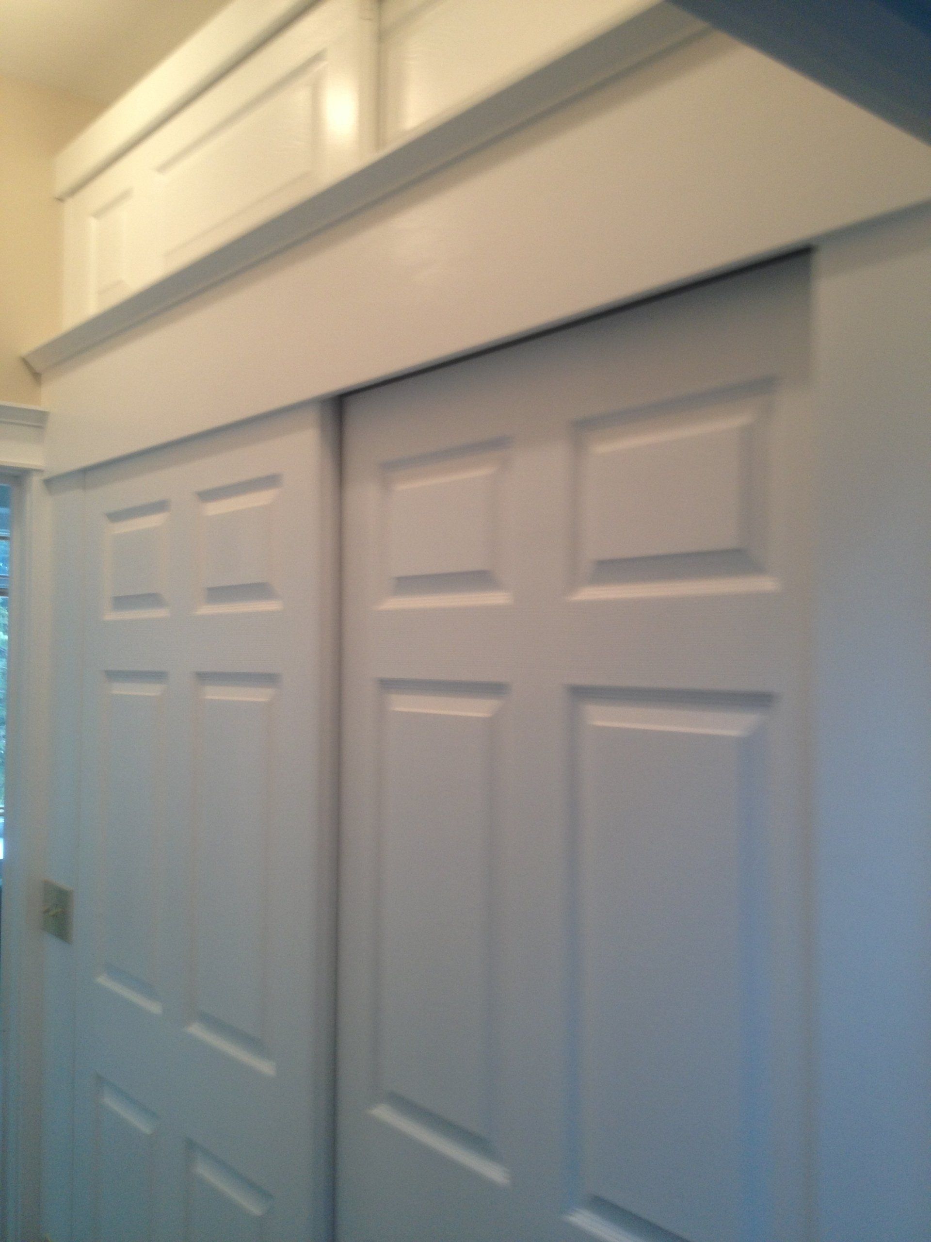 A closet with white sliding doors and a window