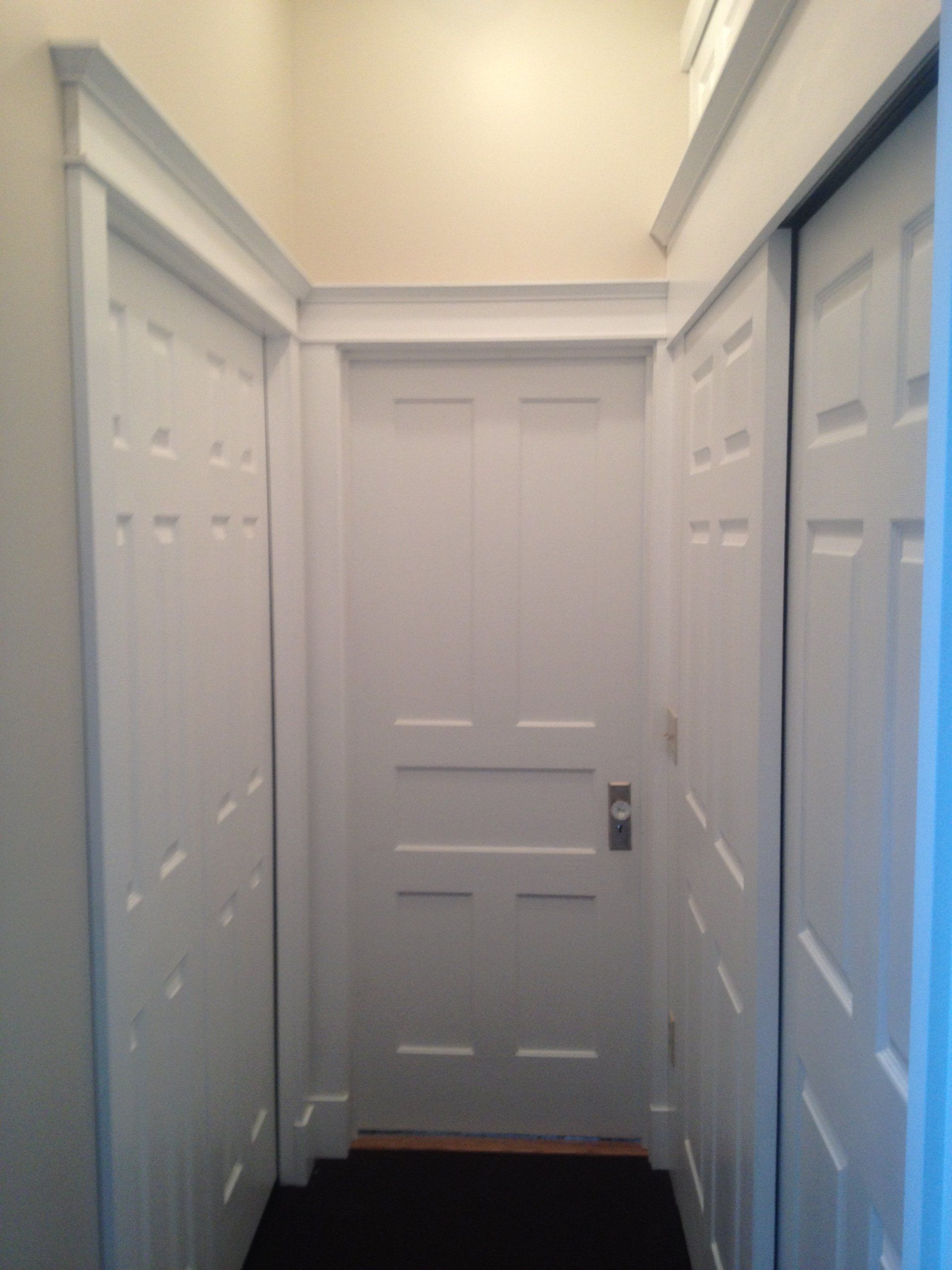 A hallway with white doors and a black floor