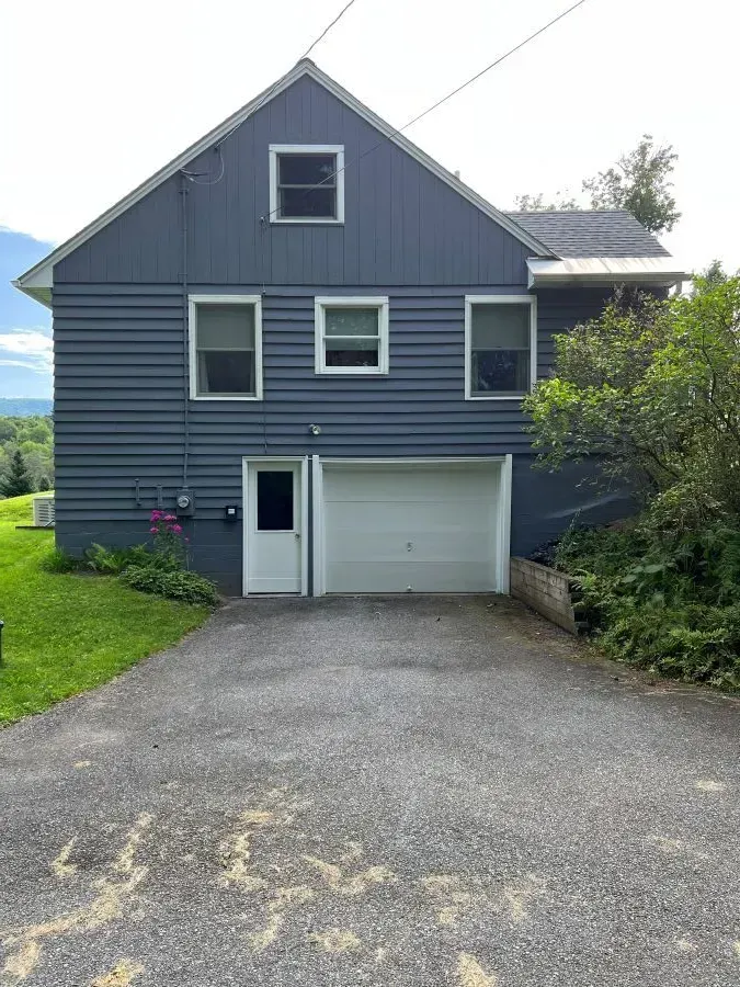 A blue house with a garage and a driveway in front of it.