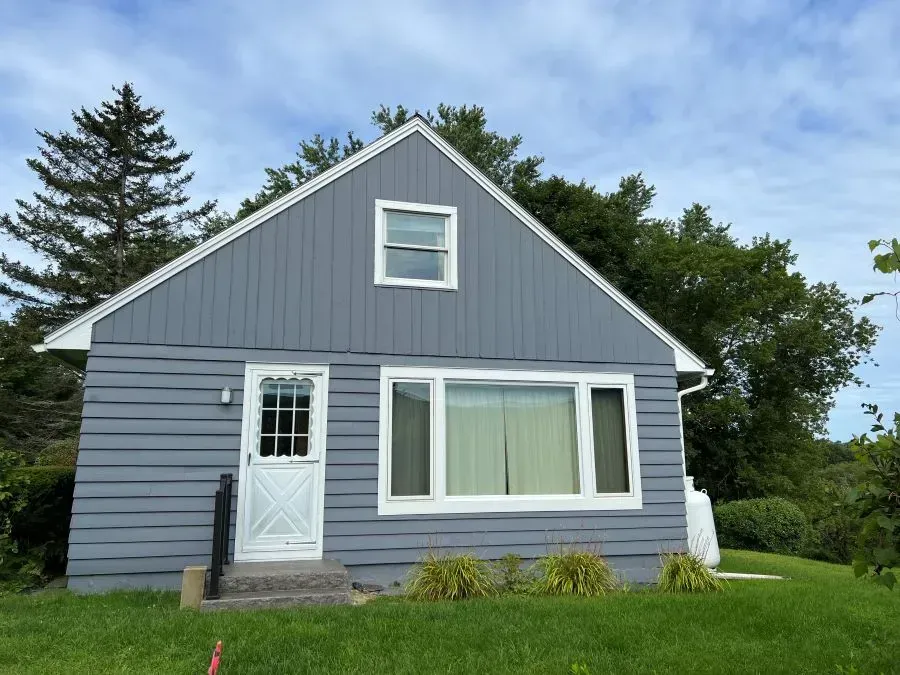 A small gray house with a white door and windows
