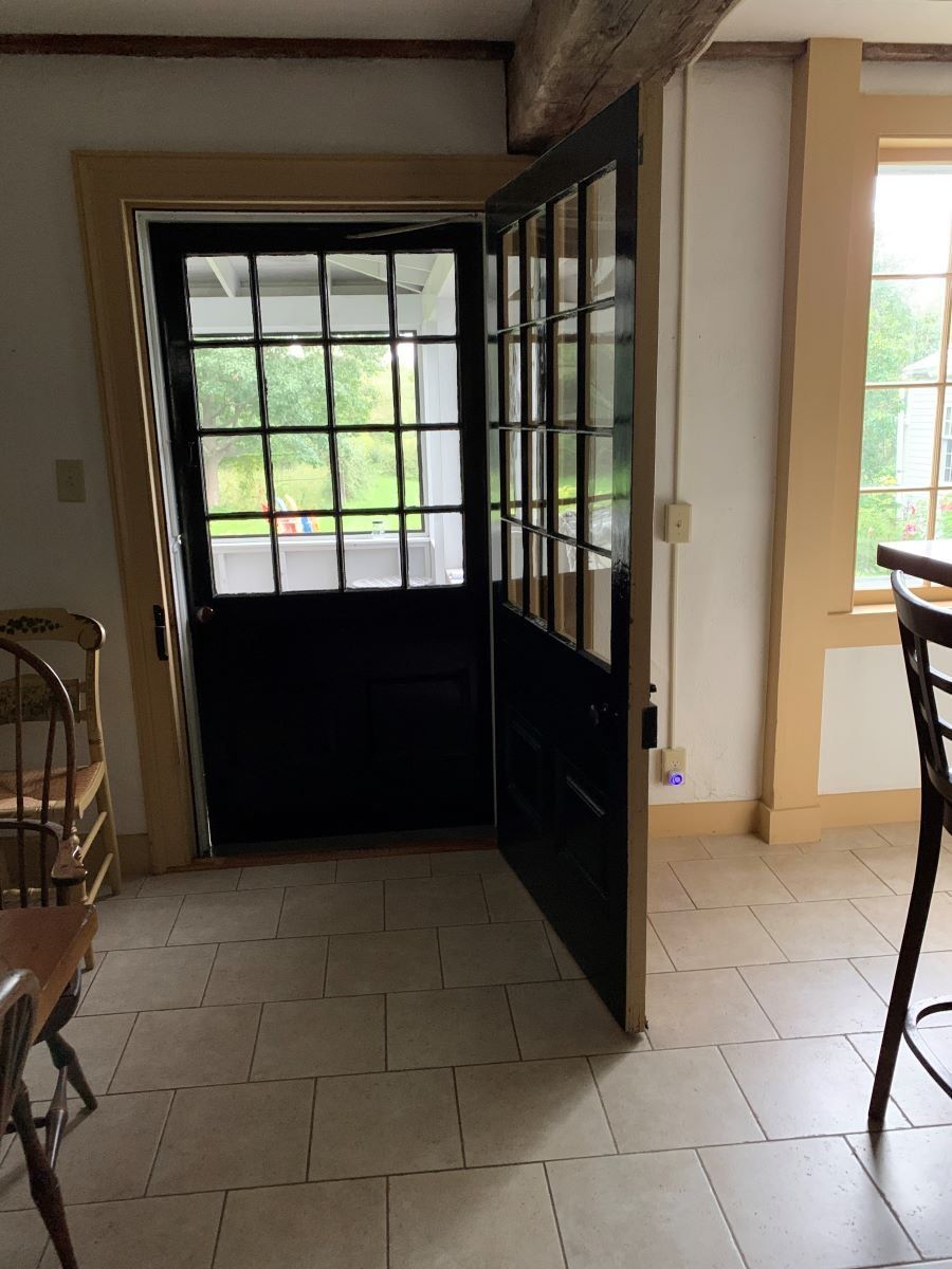 A black door is open in a room with a table and chairs.
