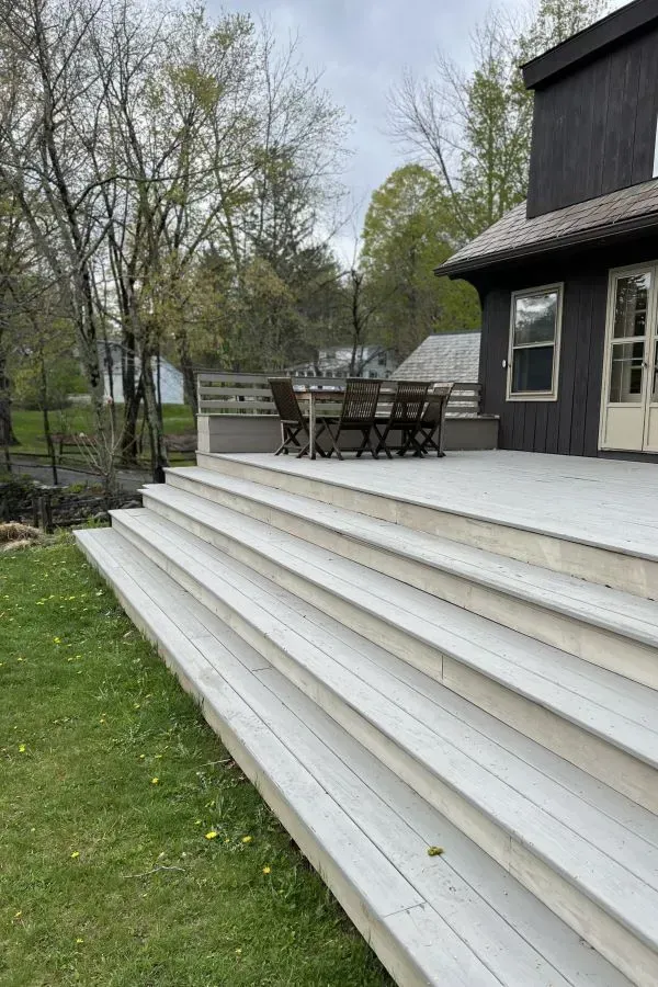 A large deck with stairs leading up to it and a table and chairs on it.