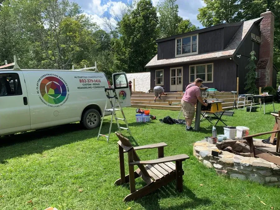 A white van is parked in the grass in front of a house.