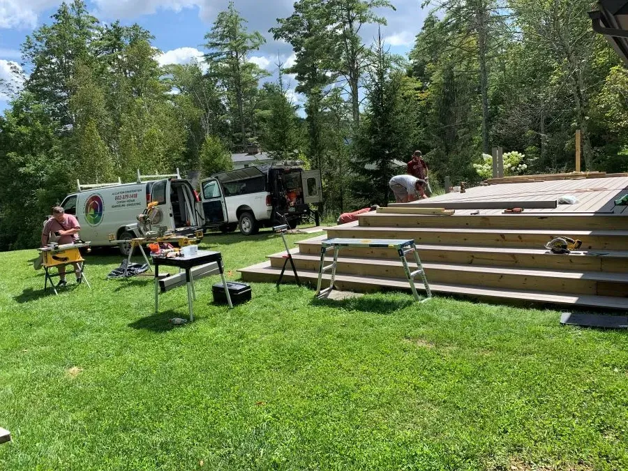 A group of people are working on a deck in a yard.