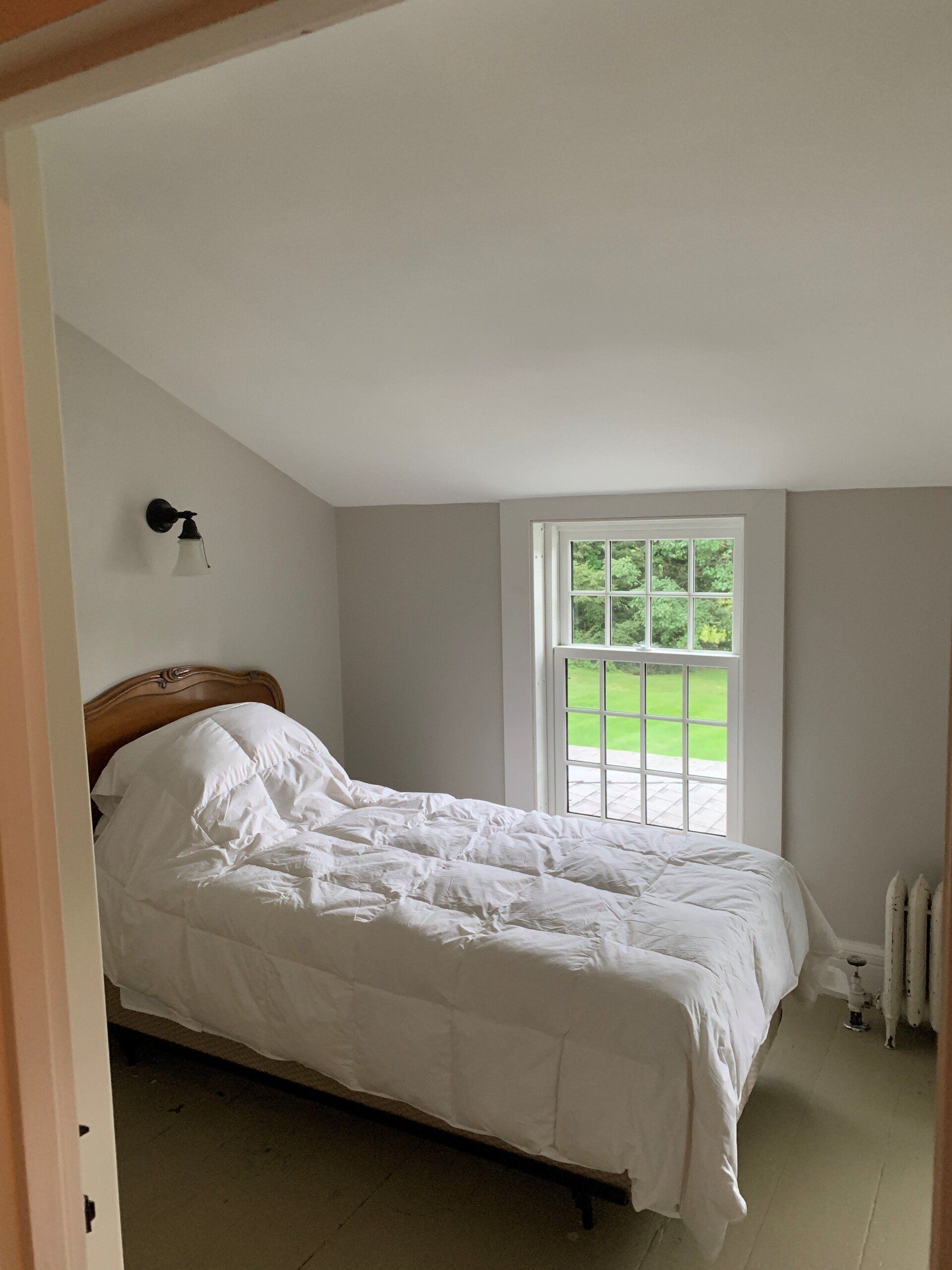 A bedroom with a bed and a window.