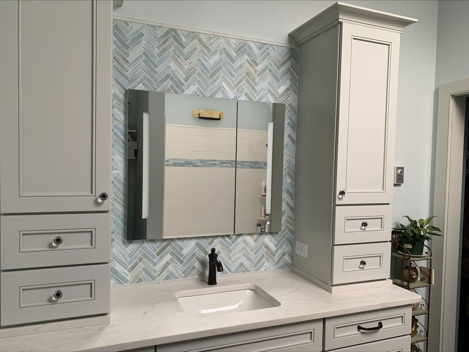 A bathroom with a sink , mirror and cabinets.