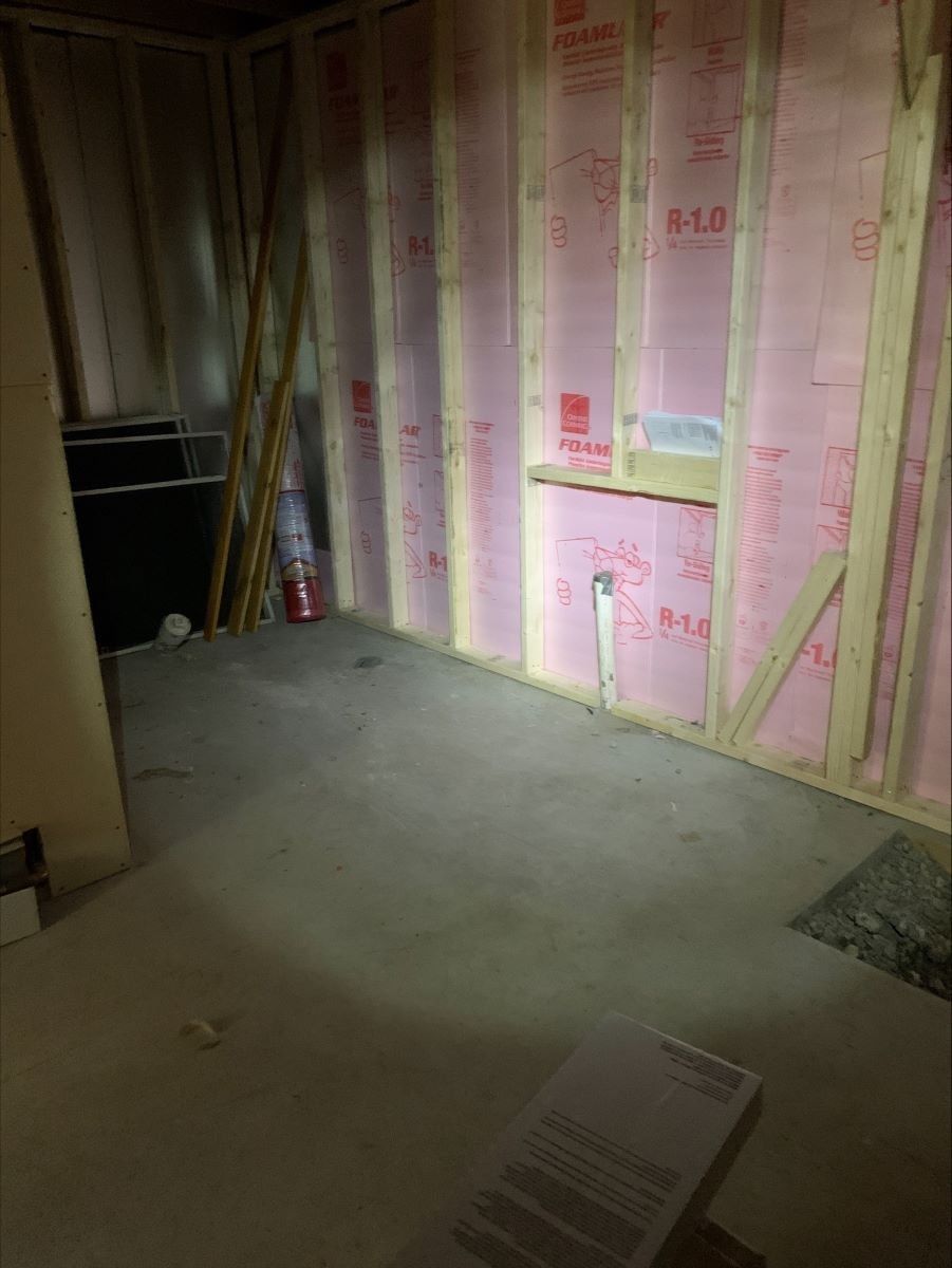 A room with pink insulation on the walls and a concrete floor.