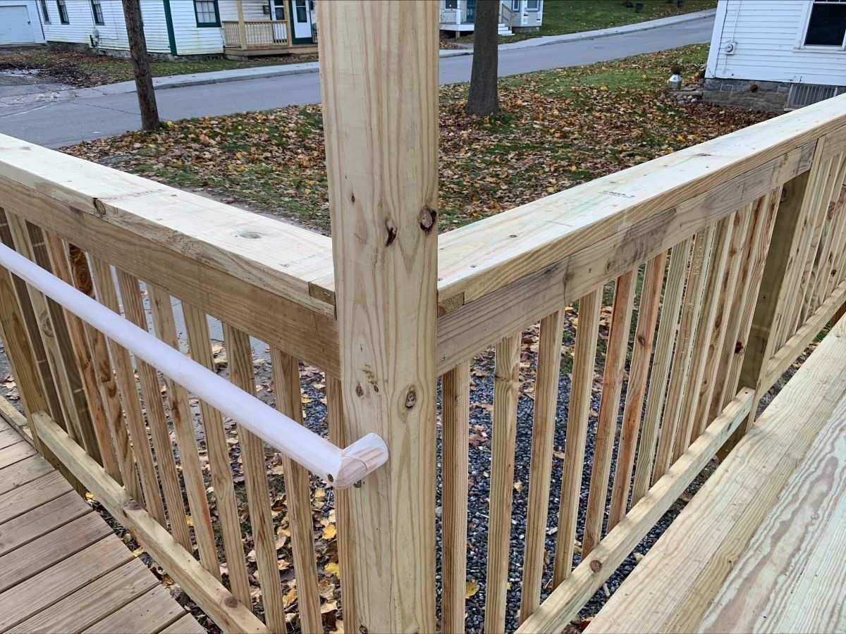 A close up of a wooden railing on a deck with a white railing.