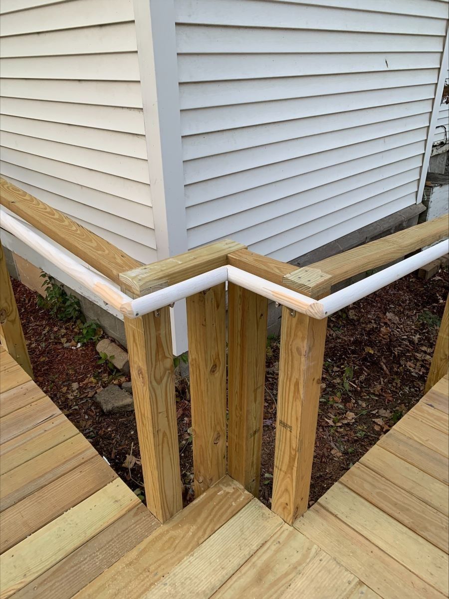 A wooden deck with stairs leading up to a white house.