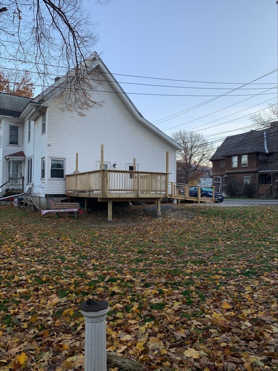 A white house with a wooden deck in front of it.