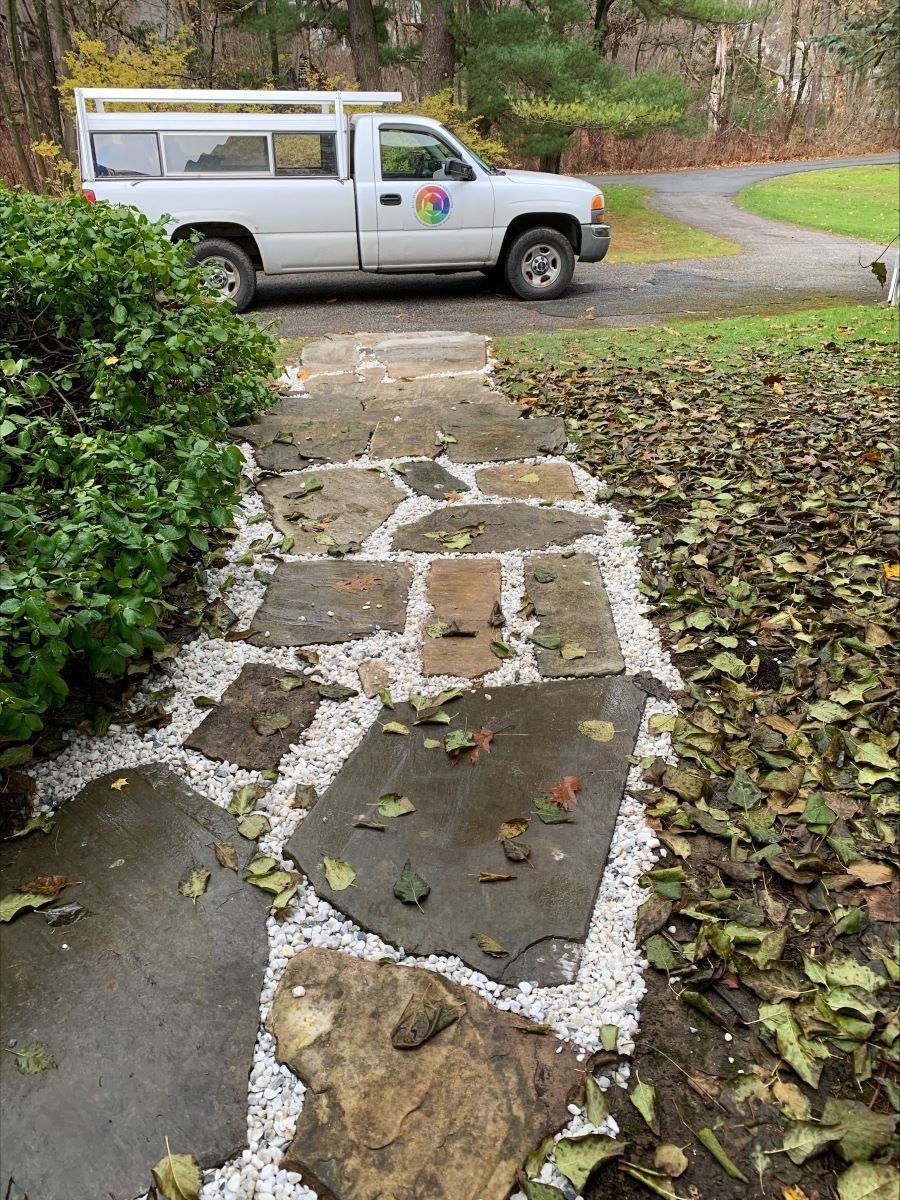 A white truck is parked next to a stone walkway.