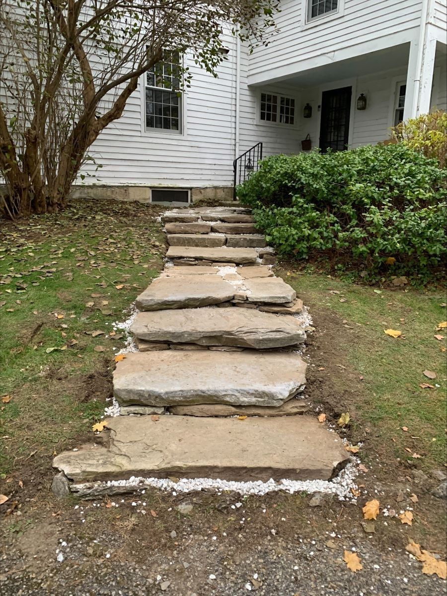 A stone walkway is being built in front of a house.