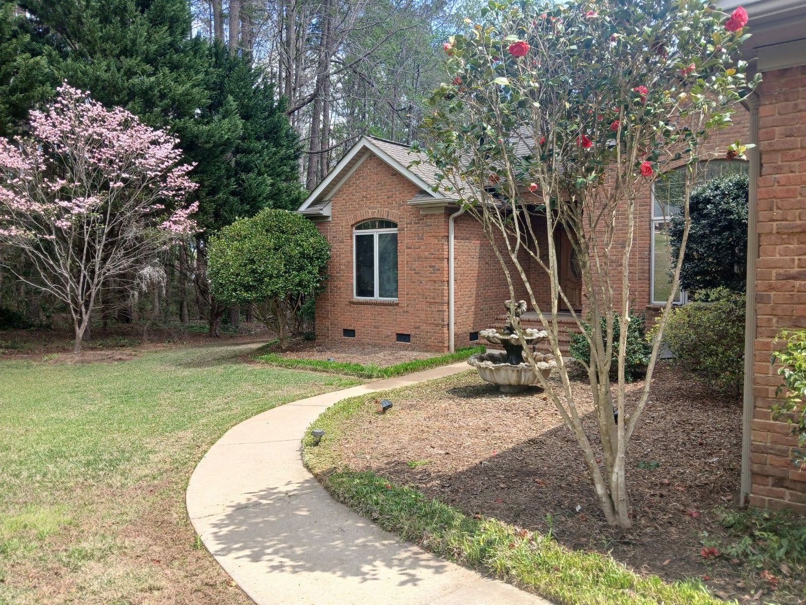 A brick house with a picnic table in front of it and a walkway leading to it.