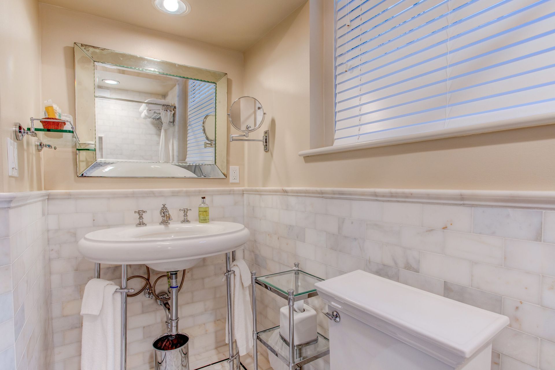 A bathroom with a sink , toilet , mirror and window.