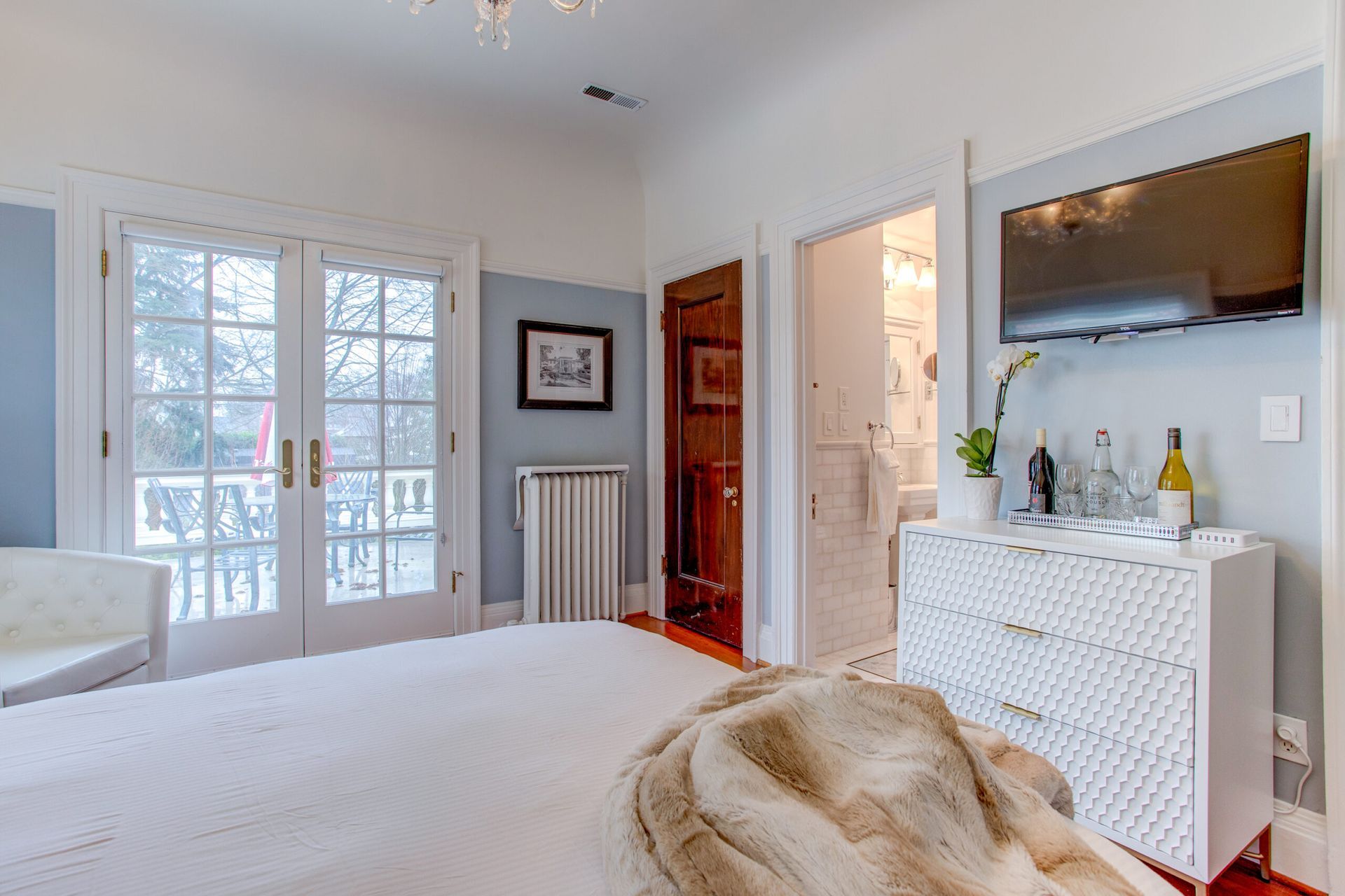 A bedroom with a bed , dresser , television and sliding glass doors.