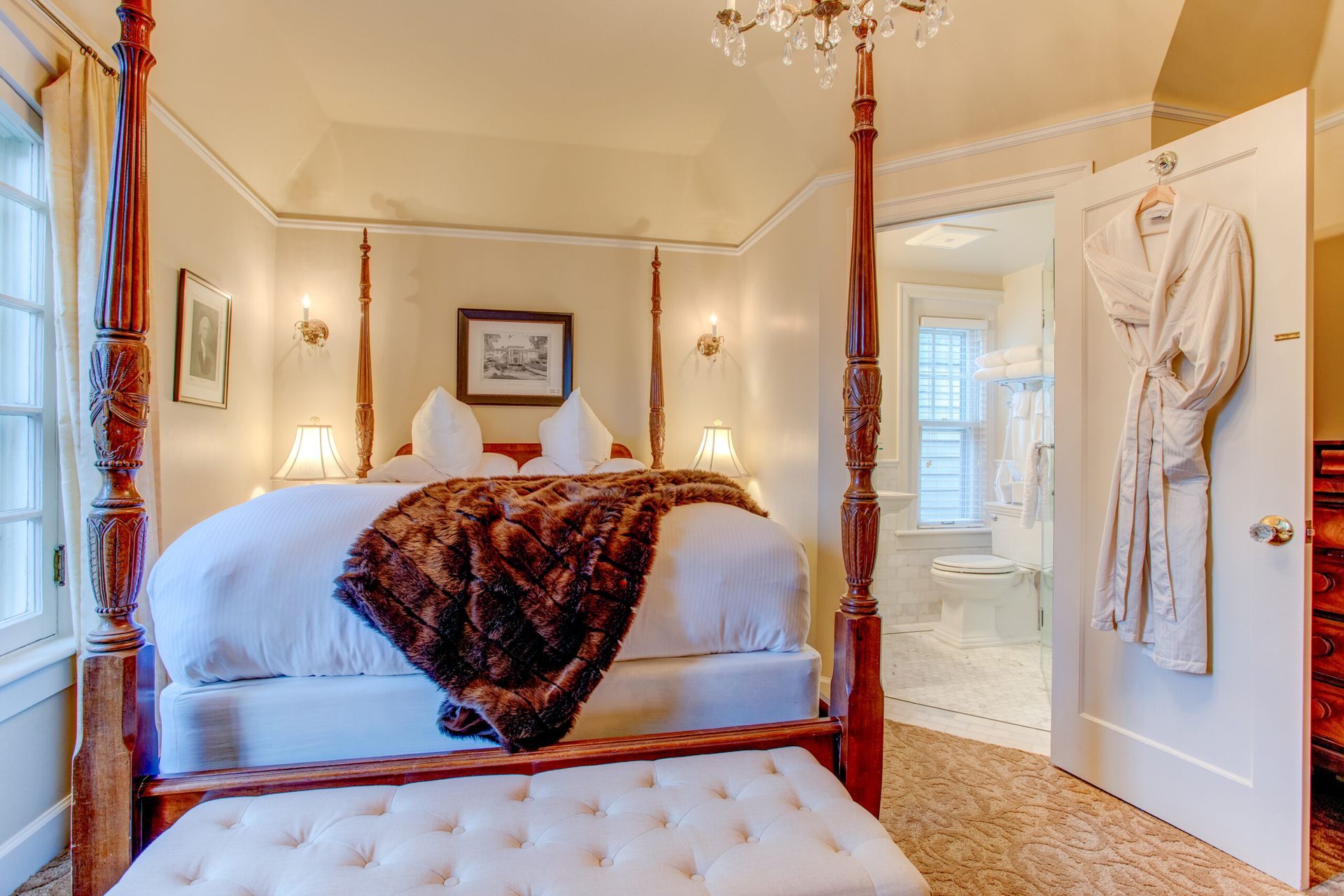 A bedroom with a four poster bed and a white ottoman.