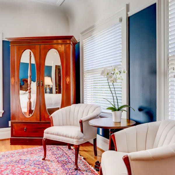 A living room with two chairs , a table and a wardrobe.