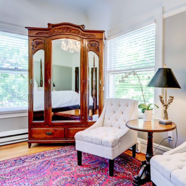 A living room with a chair a table and a mirrored wardrobe