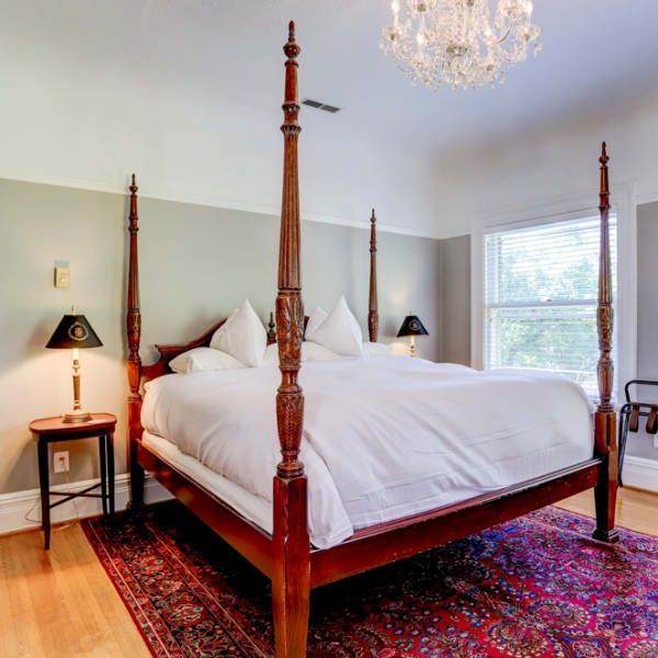 A bedroom with a four poster bed and a rug