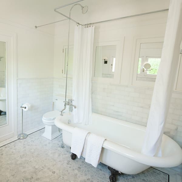 A bathroom with a bathtub toilet and mirror