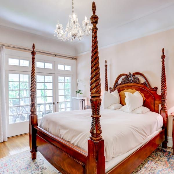 A bedroom with a four poster bed and a chandelier