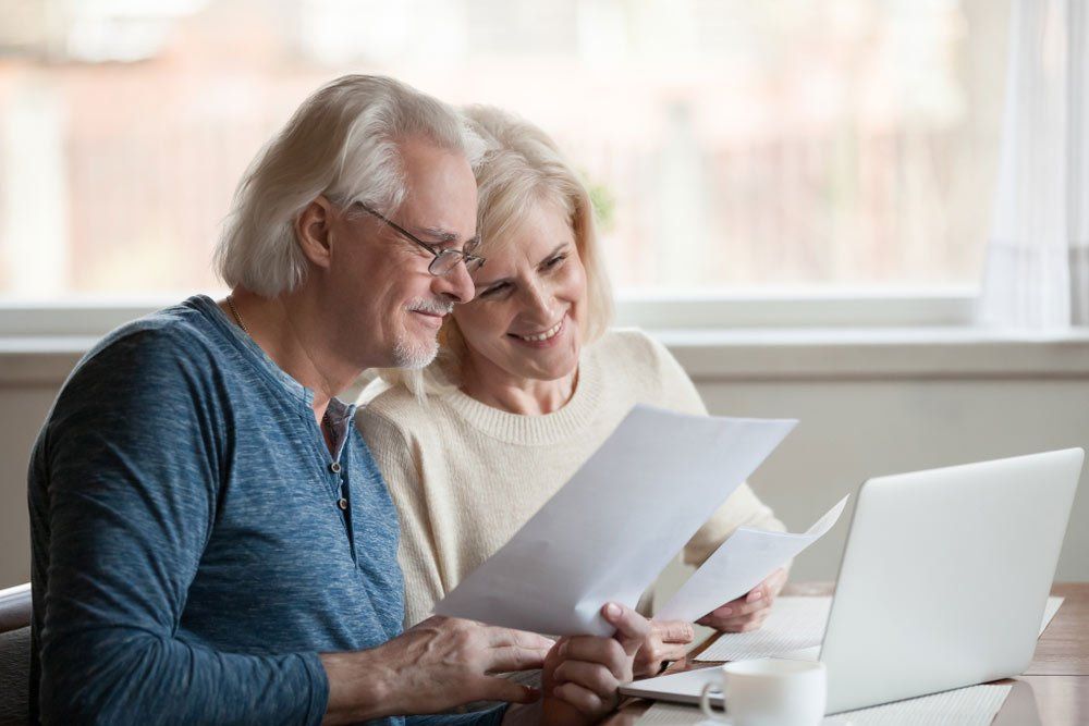 Satisfied senior couple smiling checking utility bills — Insurance Services in Yeppoon QLD