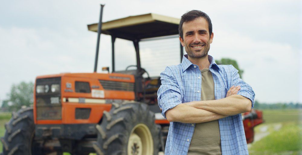 Young Farmer Standing Beside Tractor — Insurance Services in Rockhampton, QLD