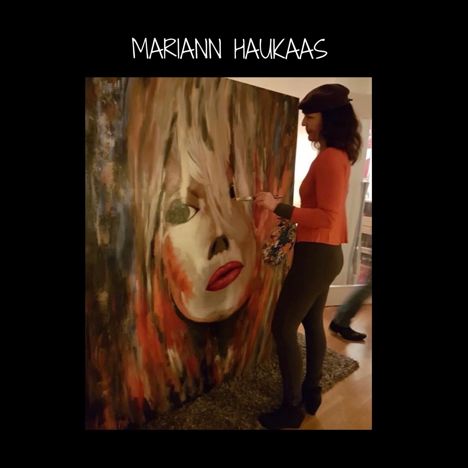 A woman is standing in front of a painting of a woman 's face and the name mariann haukaas is on the bottom