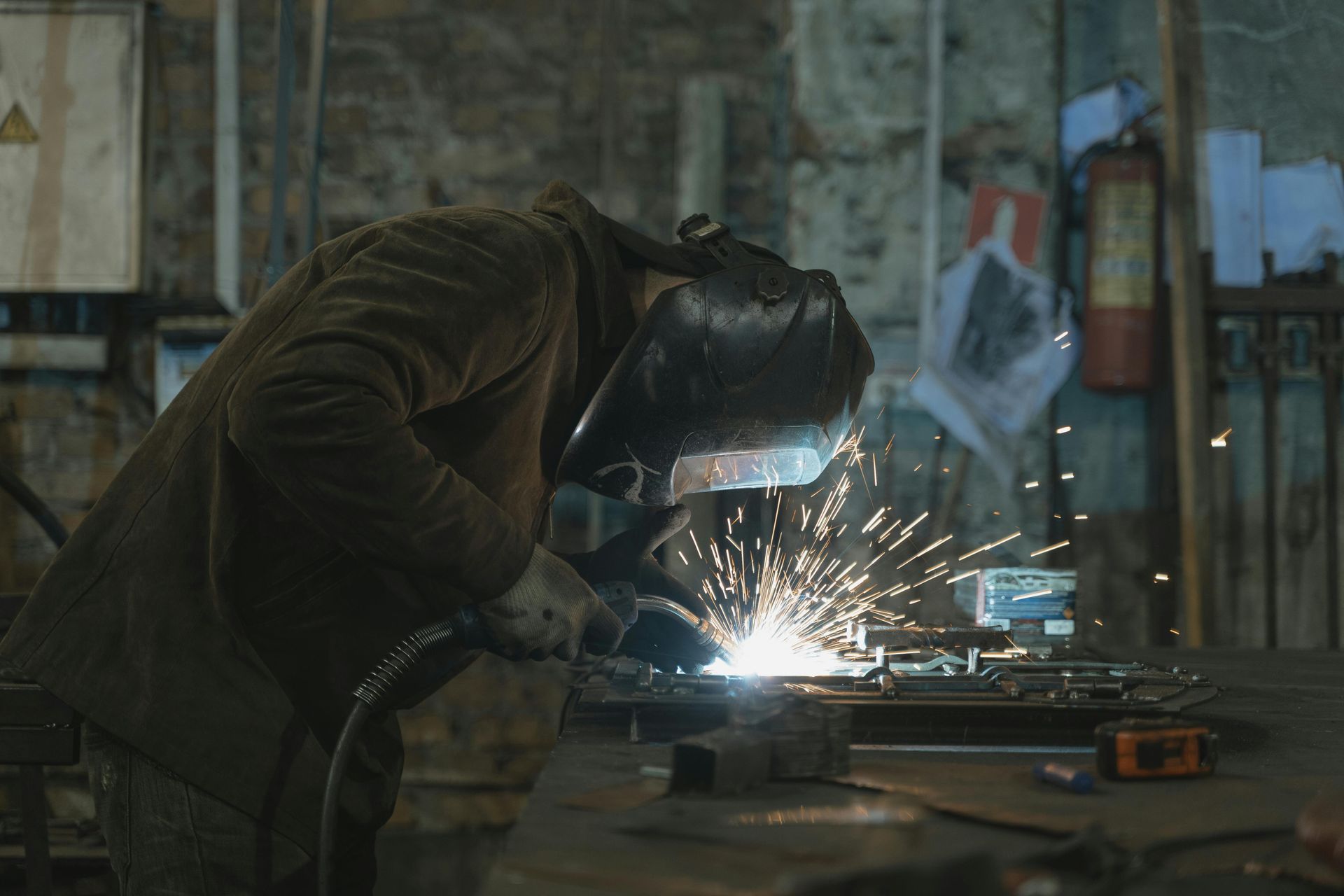A man is welding a piece of metal in a dark room
