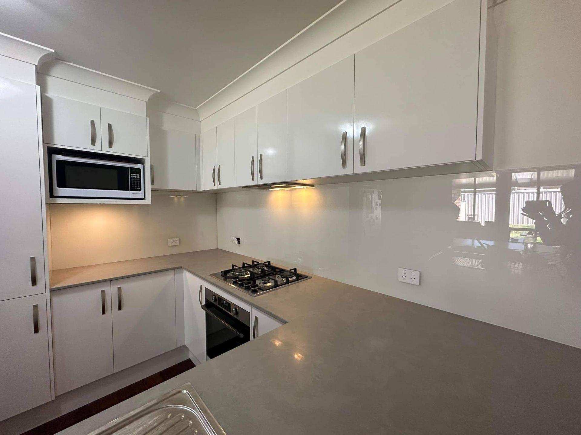 A Kitchen with White Cabinets , a Stove, a Microwave, and A Sink — Colour Splash in Lake Macquarie, NSW