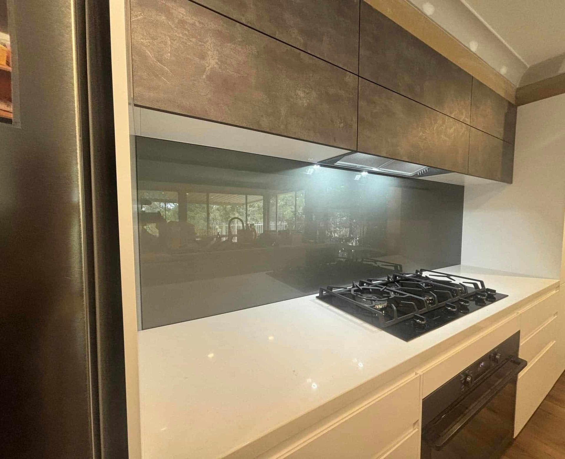 Modern Kitchen With Grey Backsplash, Gas Stove, White Countertop, and Dark Cabinets — Colour Splash in Nelson Bay, NSW