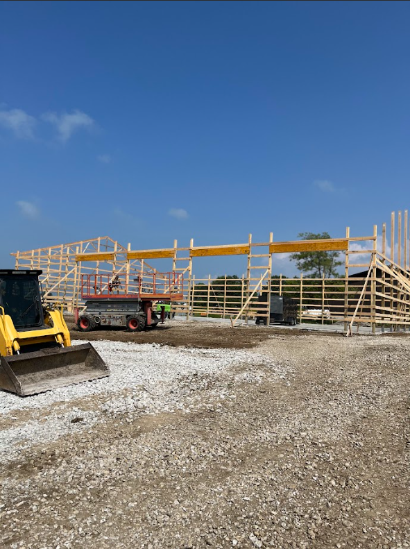A large house is being built on top of a dirt hill.