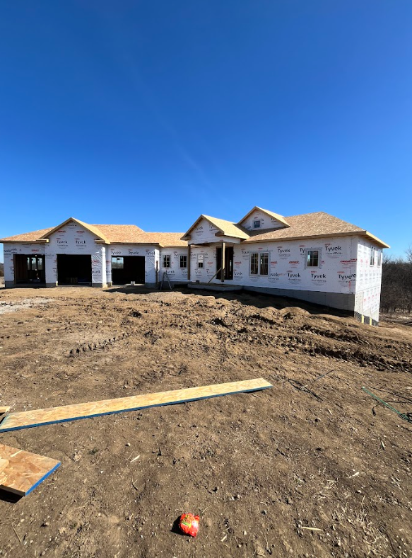 A large wooden structure is being built in a dirt field.