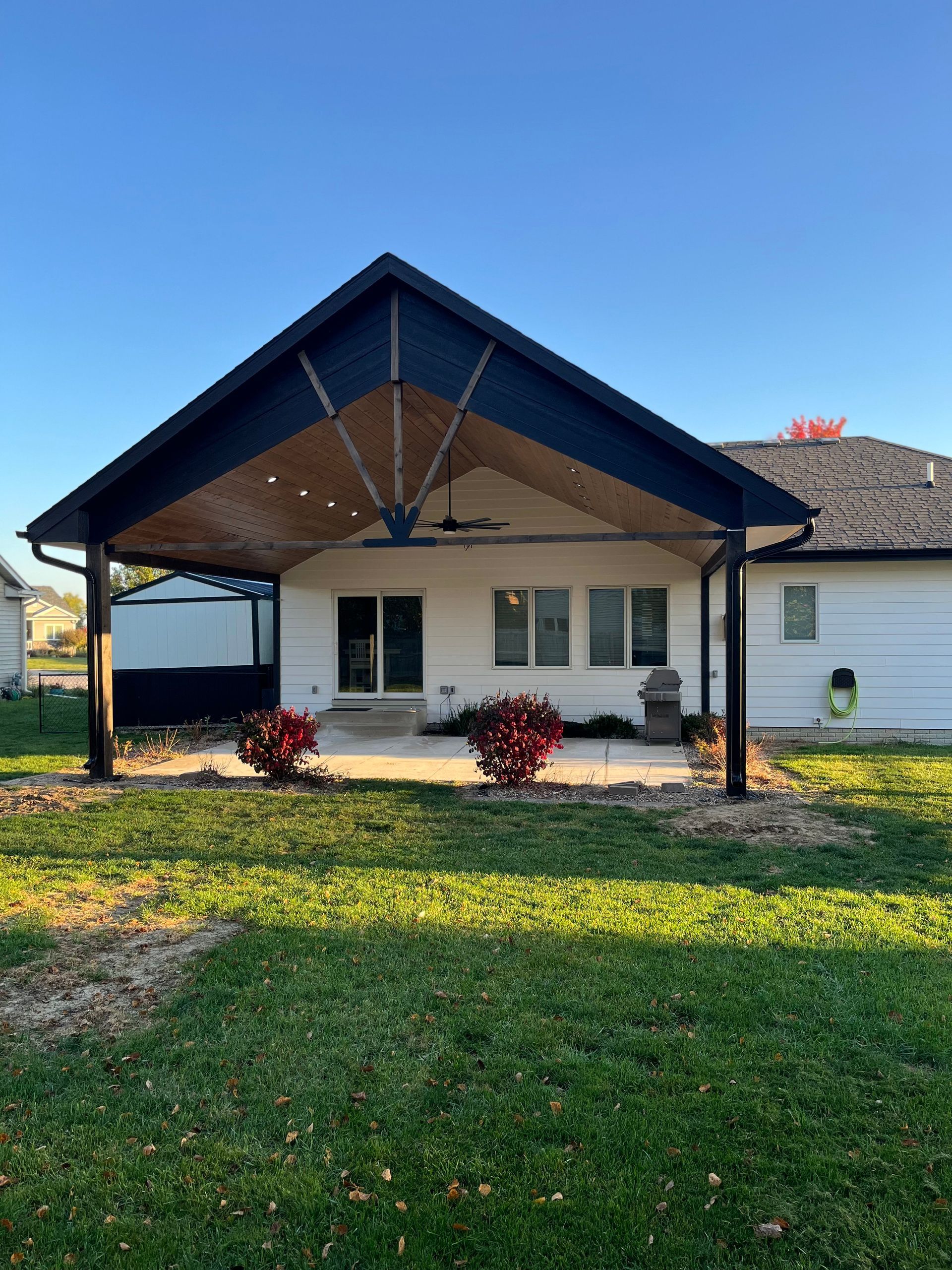 A white house with a black roof and a covered patio.