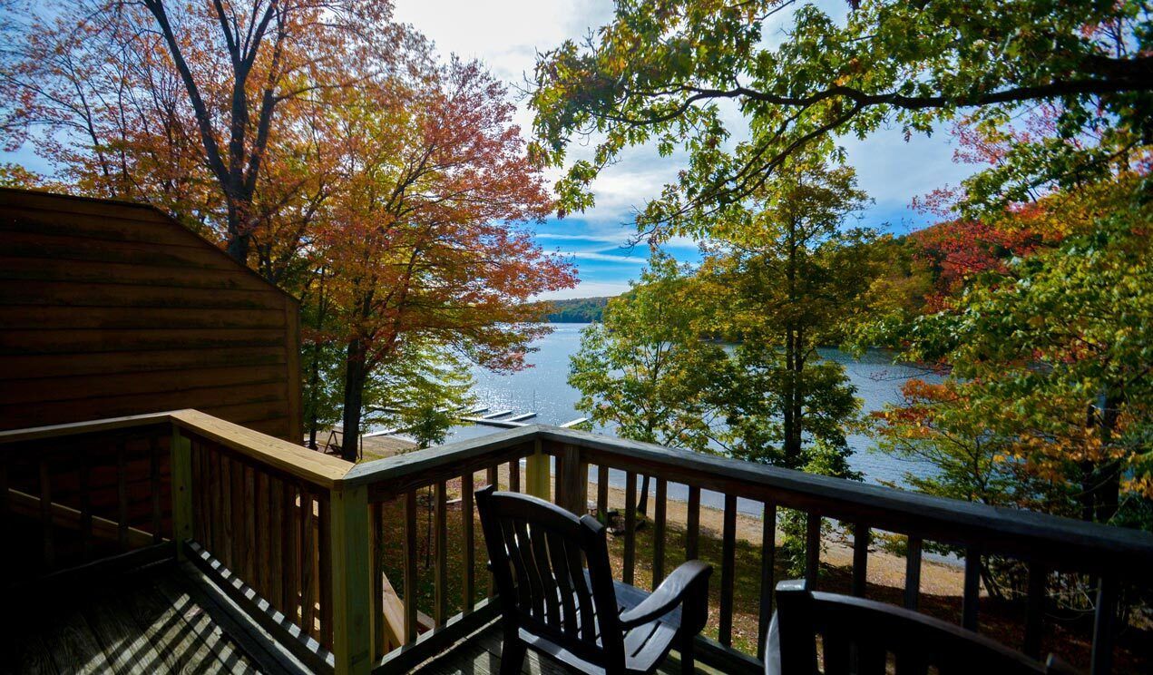 A balcony with a view of a lake and trees.